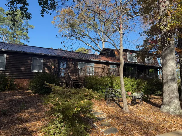 Log cabin with dark metal roof, surrounded by trees and autumn leaves.