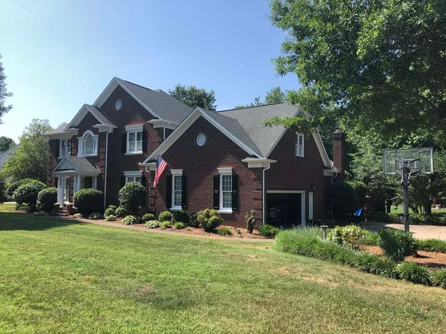 Two-story brick house with a green lawn, windows, and an American flag.