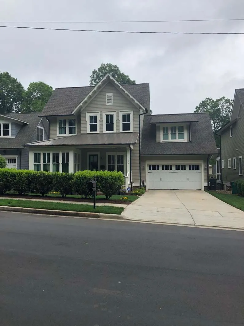 Two-story house with gray siding, attached garage, and a concrete driveway on a residential street.